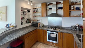 Una cucina moderna con piani in granito, mobili in legno, piano cottura in acciaio inossidabile e forno integrato.