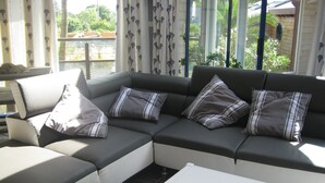 A sectional sofa with striped pillows, a white coffee table, and two remote controls on it. - Villa With Pool Indoor heated to 28 °, Jaccuzzi, Sauna (Lannion)