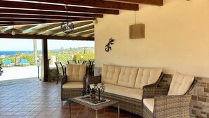 Una terrazza esterna con un divano, sedie e un tavolo in vimini.