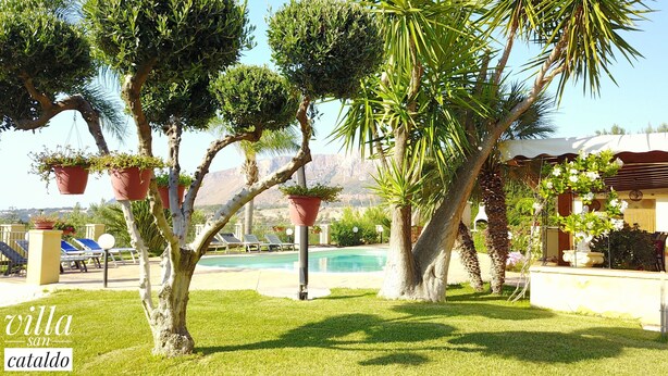 Un giardino curato con piscina, piante in vaso e vista sulle montagne.