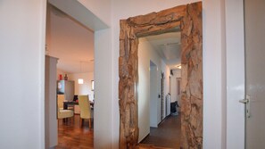 A hallway with a rustic wooden door frame leading to a dining area with a table and chairs.