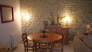 Un coin repas chaleureux avec un mur en pierre, une table en bois et des chaises.