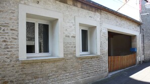 Un bâtiment en pierre avec deux fenêtres et une clôture en bois.
