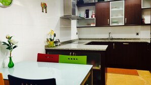 Una cocina moderna con comedor, que incluye una mesa con sillas, un reloj y un florero con flores.