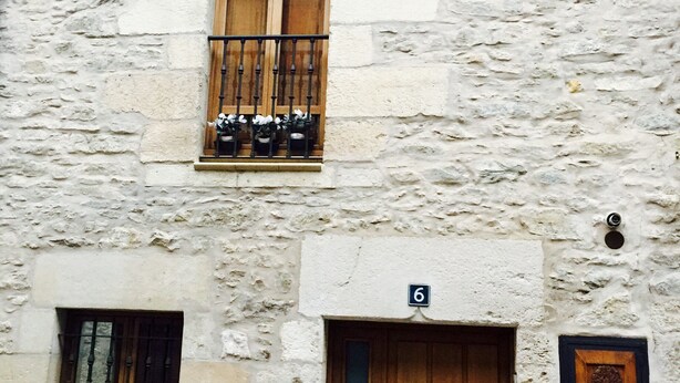 Un edificio de piedra con puerta de madera y ventana con reja de metal.