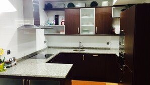 Una cocina moderna con armarios de madera oscura, encimera de granito y electrodomésticos de acero inoxidable.