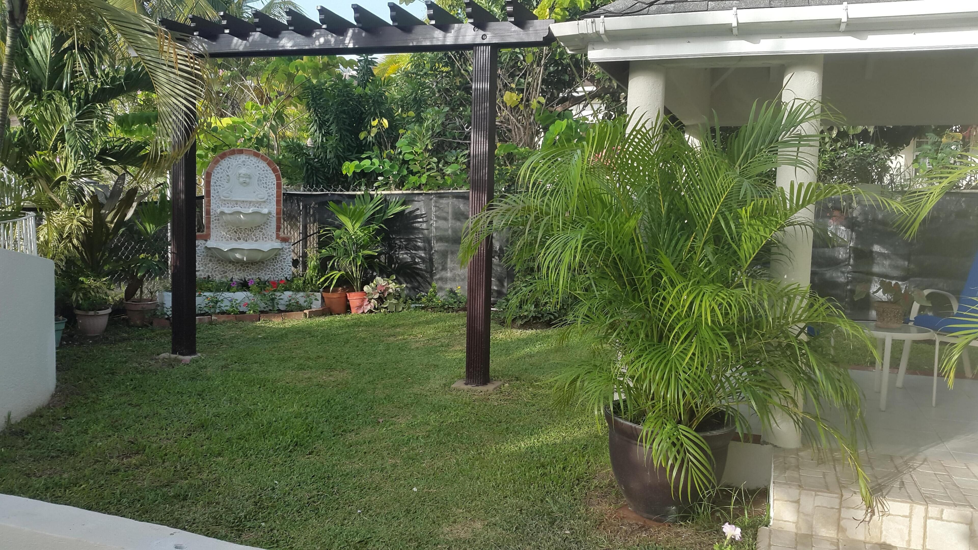 A garden with a pergola, potted plants, and a decorative fountain.