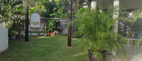 A garden with a pergola, potted plants, and a decorative fountain.