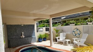Ein Poolbereich mit gefliestem Deck, einem Whirlpool und weißen Liegestühlen.