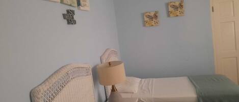 A bedroom with two beds, a nightstand with a lamp, and wall art.