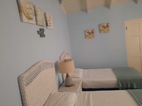 A bedroom with two beds, a nightstand with a lamp, and wall art. - Affordable Two Bedroom Two Bathroom Apartment With Private Pool (Holetown)