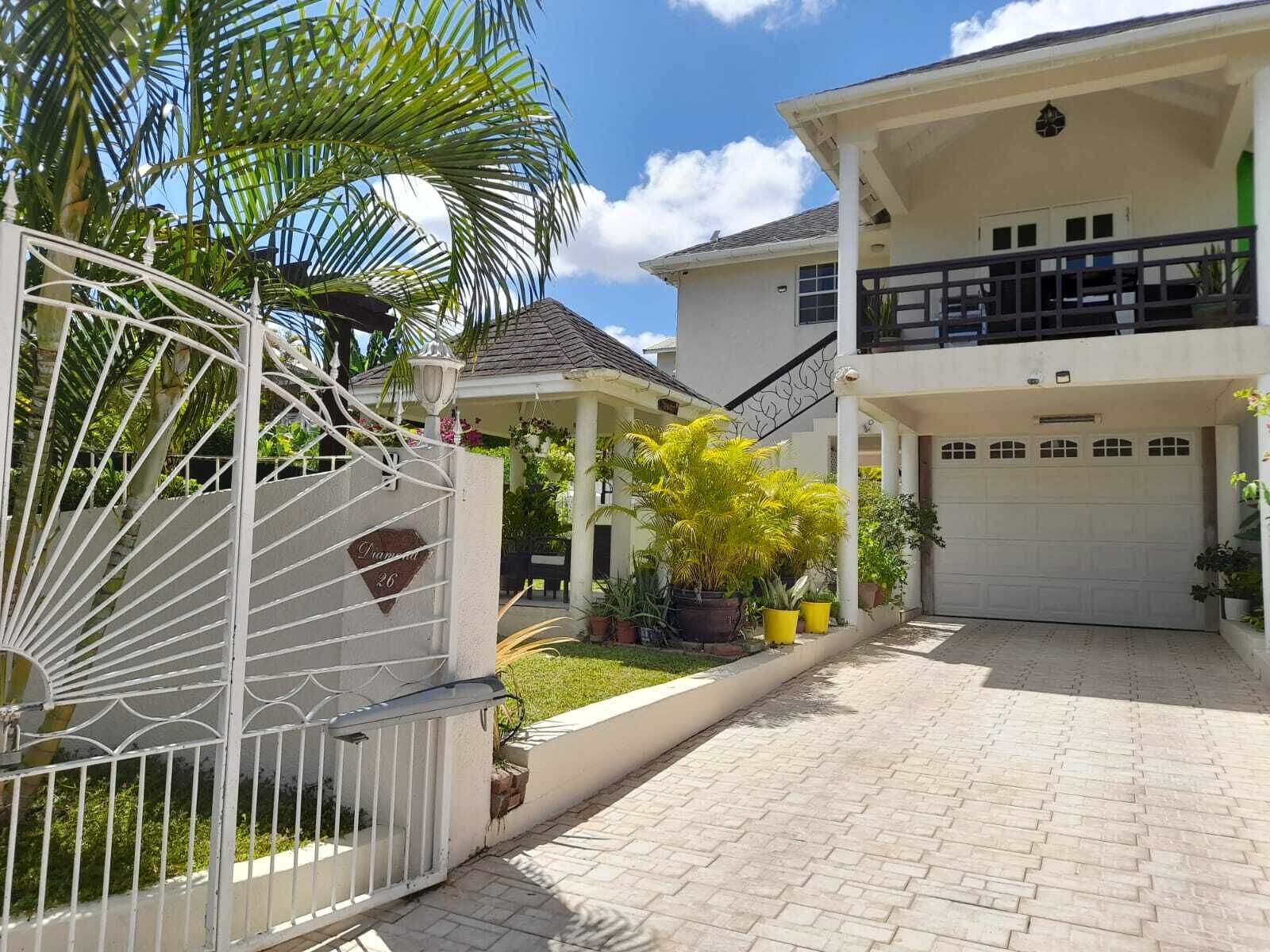 A two-story house with a covered patio, a garage, and a gated entrance.