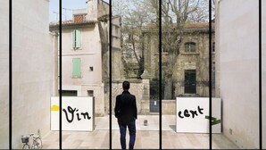 Un bâtiment moderne avec une façade en verre, et une personne se tenant au centre.