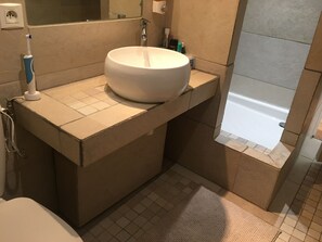 Een bad/douchecombinatie, een haardroger, handdoeken, zeep