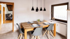 A dining area with a wooden table, four grey chairs, and black pendant lights. - Country Living in the southern Eifel, vacation apartment in the Sauertal N° 2 (Ralingen)