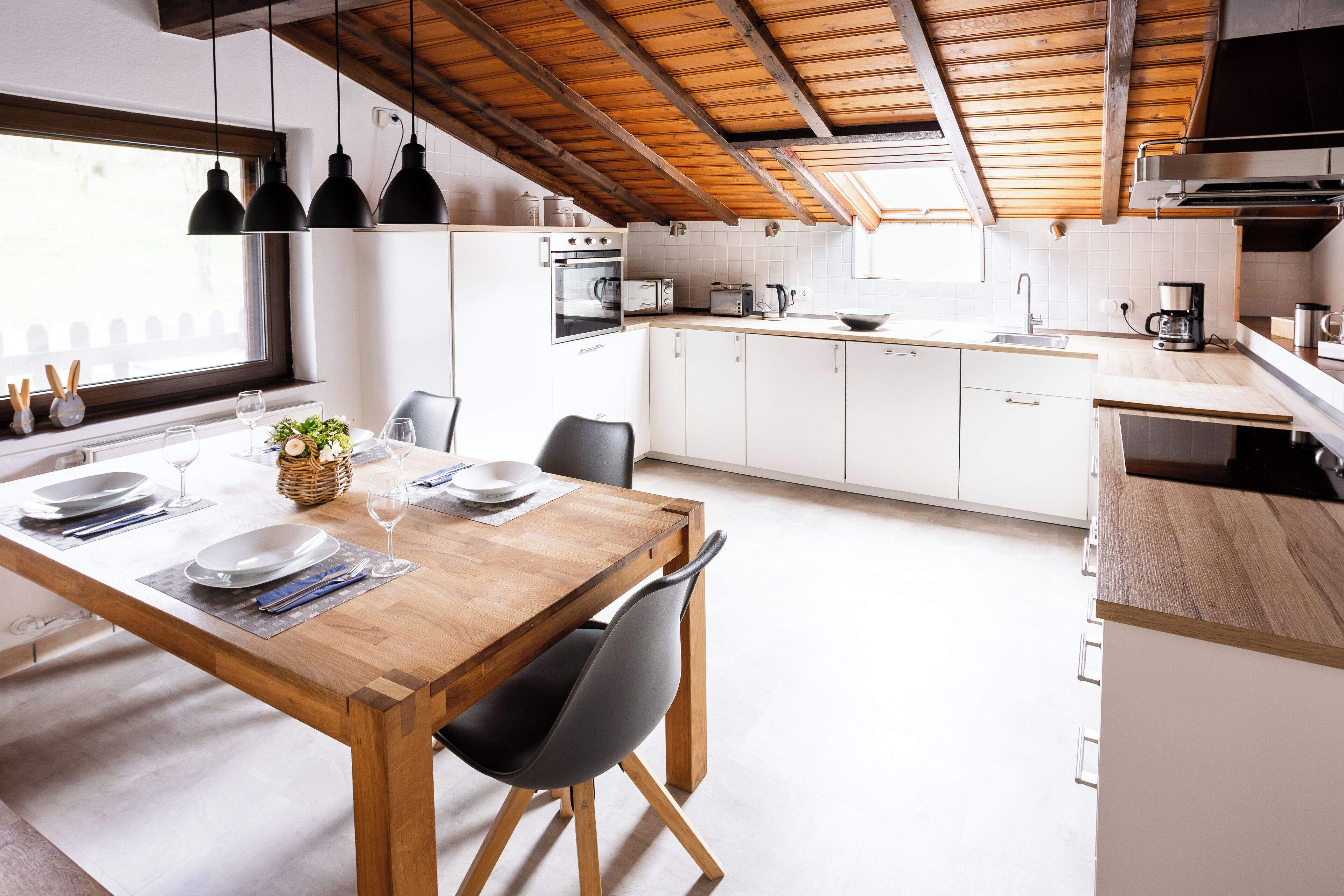 Eine moderne Küche mit weißen Schränken, einem Holztisch und schwarzen Stühlen.