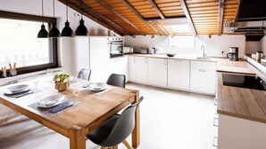 A modern kitchen with white cabinets, a wooden dining table, and black chairs. - Country Living in the southern Eifel, vacation apartment in the Sauertal N° 2 (Ralingen)