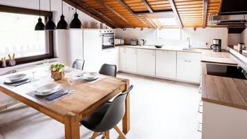 Eine moderne Küche mit weißen Schränken, einem Holztisch und schwarzen Stühlen.