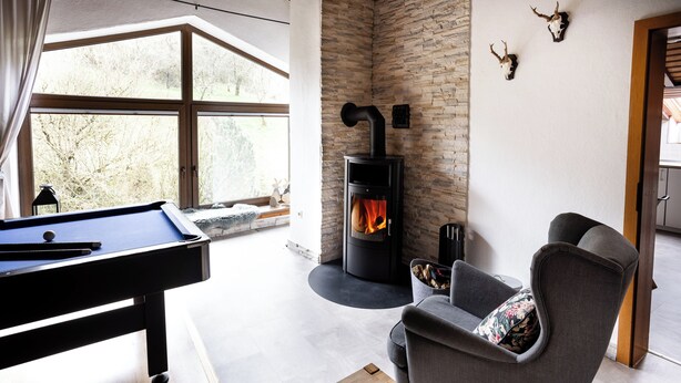 A modern living room with a pool table, a fireplace, and a comfortable seating area. - Country Living in the southern Eifel, vacation apartment in the Sauertal N° 2 (Ralingen)
