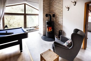 A modern living room with a pool table, a fireplace, and a comfortable seating area. - Country Living in the southern Eifel, vacation apartment in the Sauertal N° 2 (Ralingen)