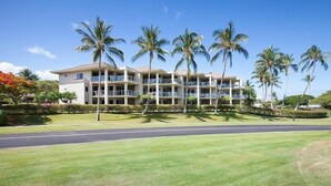 A multi-story hotel with balconies, surrounded by palm trees and a well-maintained lawn. - Partial Ocean Views, Top Floor. Beach Gear Included.  Vista Waikoloa A304 (Waikoloa Beach Resort)