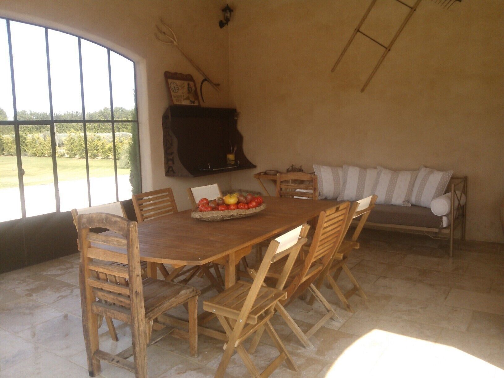 A dining area with a wooden table and chairs, a fruit bowl, and a sofa.