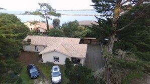 A house with a tiled roof, a driveway, and two cars parked in the front.