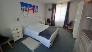 Un dormitorio con cama, mesitas de noche, una silla, un armario y un cuadro en la pared.