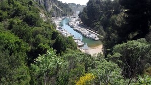 A marina with boats docked along a river surrounded by dense greenery and rocky cliffs. - Private pool & south-facing garden, absolute calm,  close to the sea. (La Ciotat)
