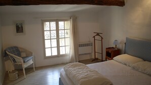 Ein Schlafzimmer mit Bett, Stuhl, Fenster und Nachttisch.