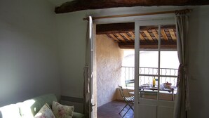Ein Zimmer mit einem grünen Sofa, einer Holzbalkendecke und einem Balkon mit Tisch und Stühlen.