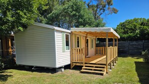 Ein kleines, eingeschossiges Mobilheim mit Veranda und umzäunter Garten.