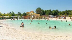 Ein großer Außenpool mit Wasserrutsche und Sandstrand.