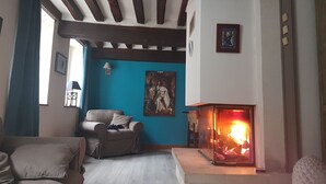 A living room with a fireplace, a blue wall, and a painting. - Logis la Rotourelle  (Torcy-le-Grand)