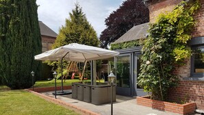A patio area with a covered seating area, a playset, and a glass-enclosed structure. - Logis la Rotourelle  (Torcy-le-Grand)