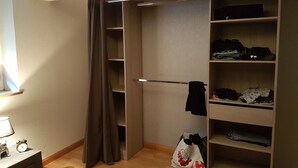 A walk-in closet with shelves for clothes, a hanging rod, and a bag on the floor. - Logis la Rotourelle  (Torcy-le-Grand)