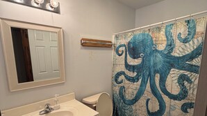 Bagno con lavandino, specchio, servizi igienici e tenda da doccia con motivo mappa.