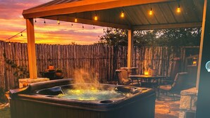 A hot tub under a wooden pergola with string lights, surrounded by outdoor furniture. - Love of the View  - Glen Rose Luxury Cottage (Glen Rose)