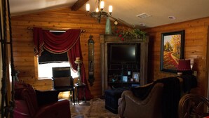 A cozy living room with a fireplace, a television, and a bookshelf. - Love of the View  - Glen Rose Luxury Cottage (Glen Rose)