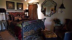 A bedroom with a large bed, a small bench, a mirror, and a chandelier. - Love of the View  - Glen Rose Luxury Cottage (Glen Rose)