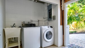 A compact laundry area with a washing machine, a dryer, and a sink. - A Shore Thing - Relaxing Island Living , Large Heated Pool, Boat Lift (Holmes Beach)