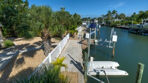 A marina with boats docked, a pathway, and palm trees. - A Shore Thing - Relaxing Island Living , Large Heated Pool, Boat Lift (Holmes Beach)