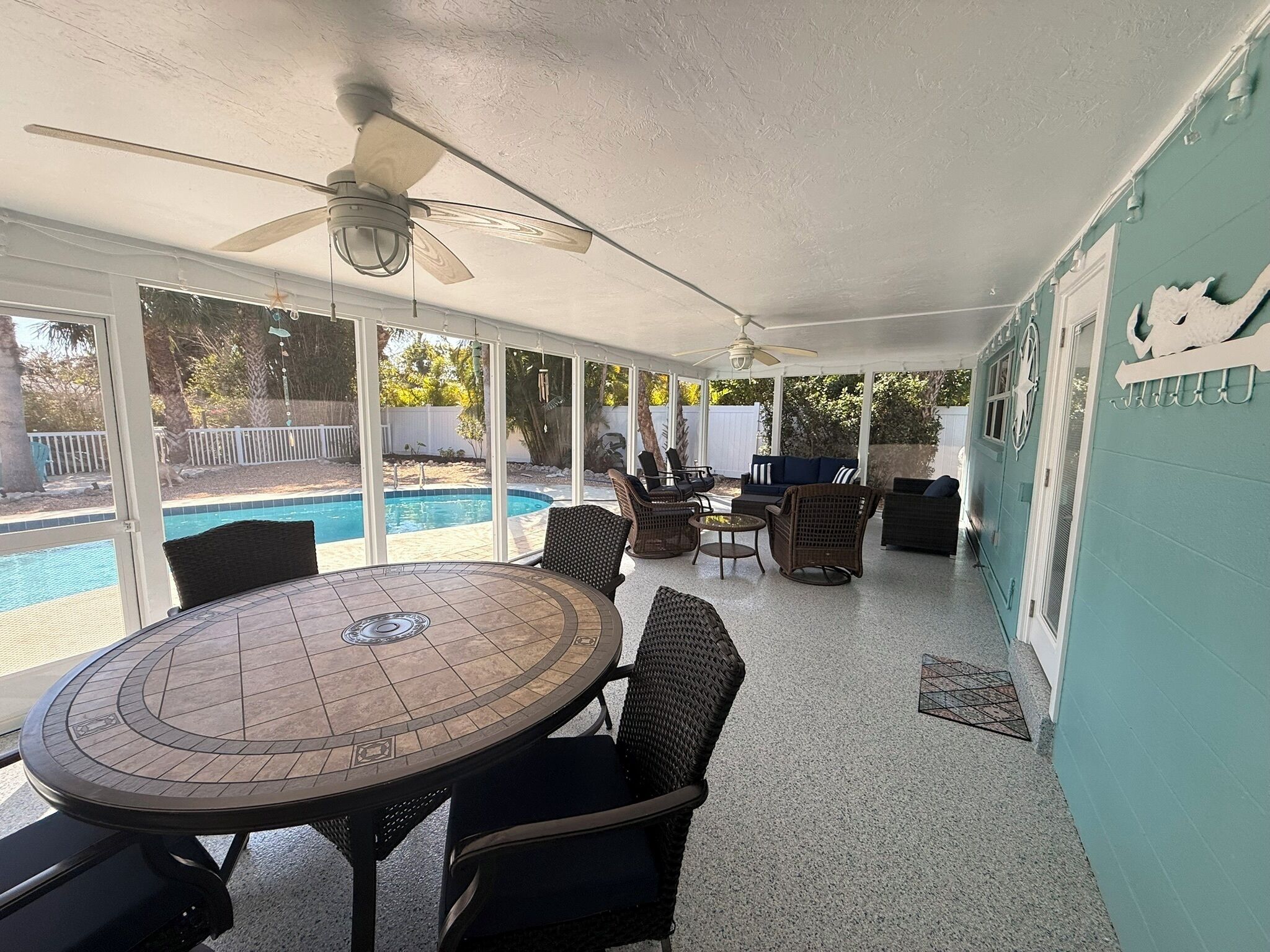 Un patio cubierto con piscina, mobiliario exterior y ventilador de techo.
