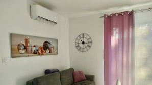 Ein Wohnzimmer mit grauem Sofa, einer Wanduhr und einem Bild von Kerzen.