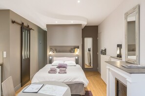 Une chambre d’hôtel moderne équipée d’un lit, de tables de chevet, d’un miroir et d’une cheminée.