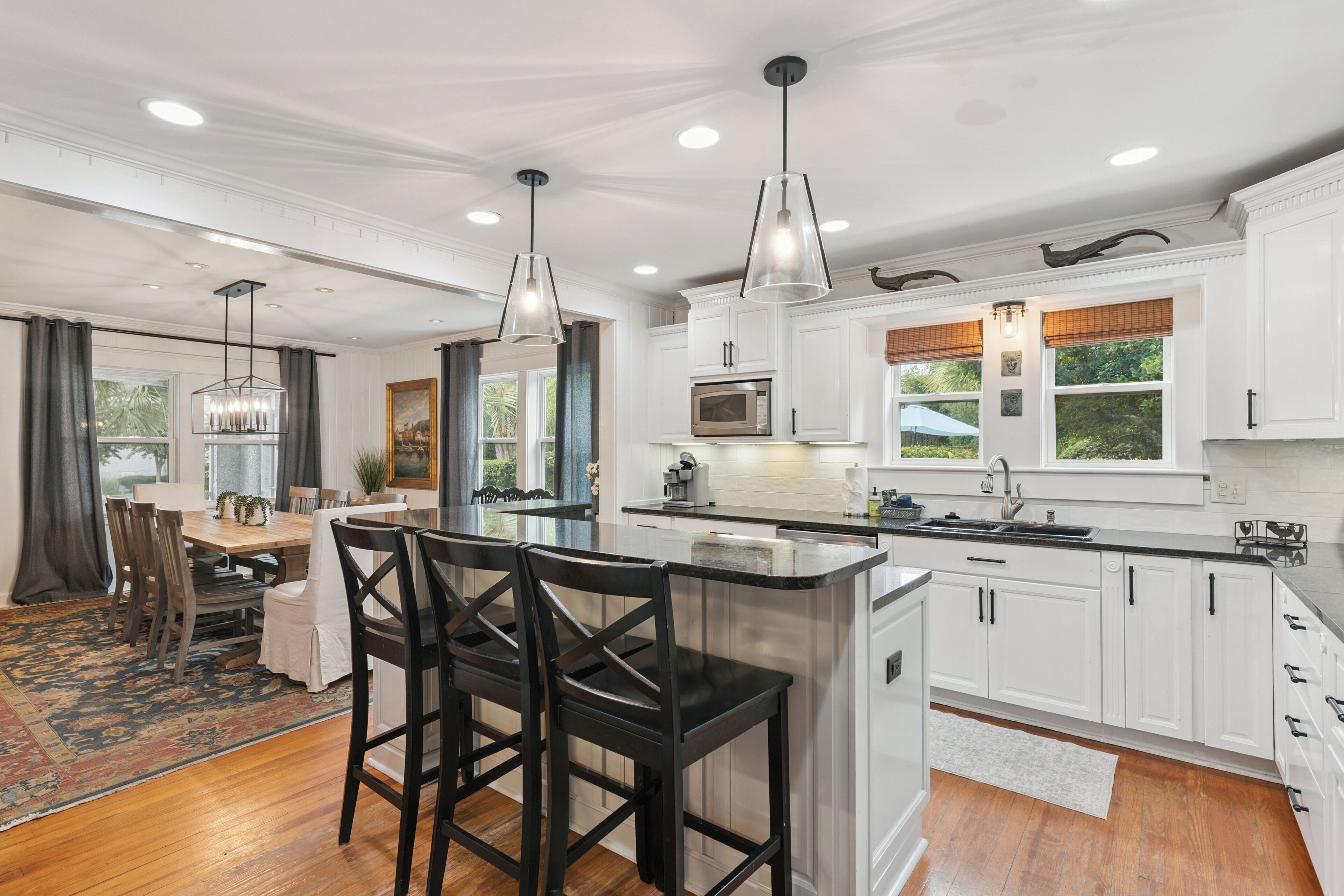 A modern kitchen with white cabinetry, a central island, and pendant lighting.