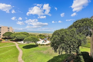 A landscaped courtyard with a playground, a clear view of the ocean, and a building in the background.