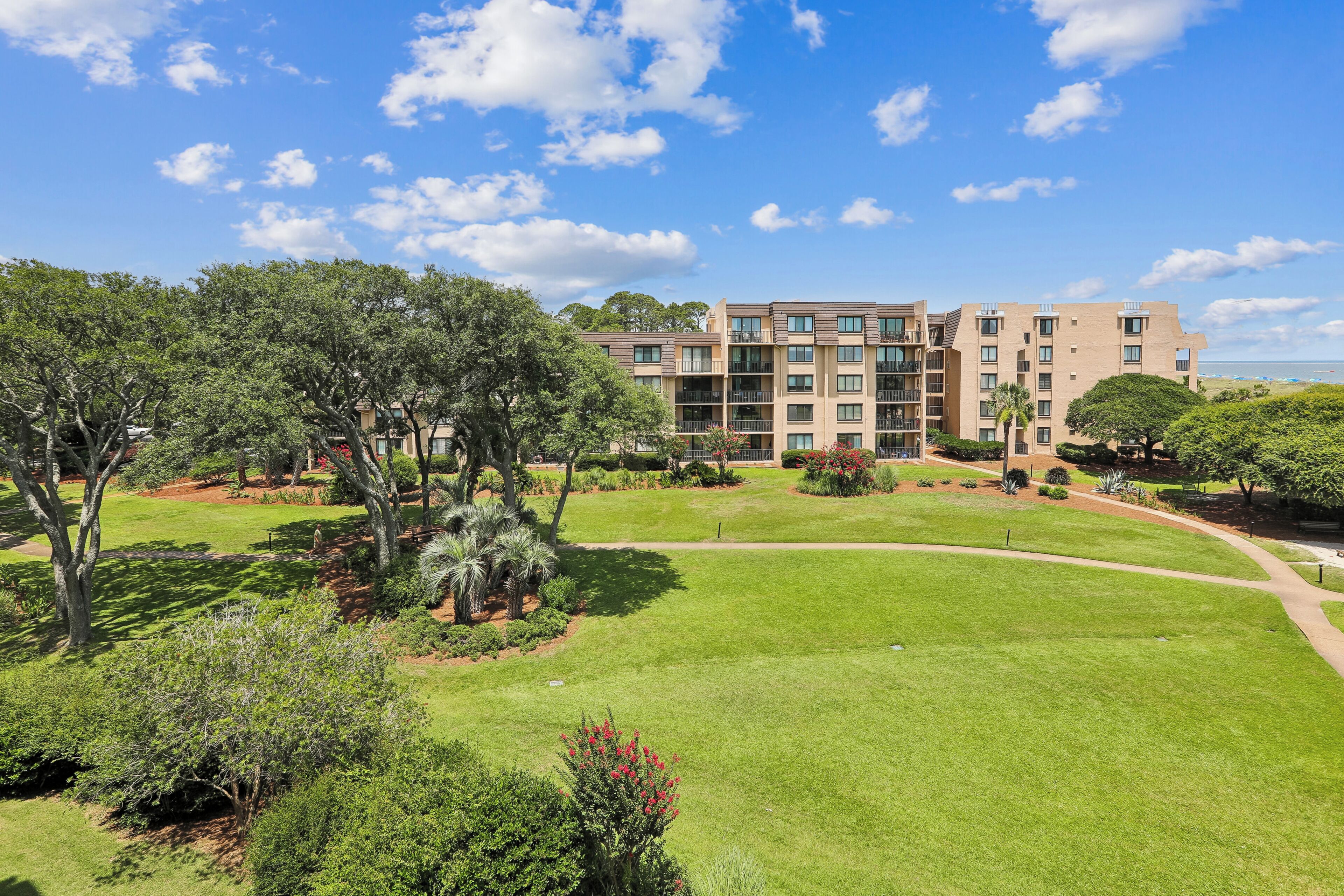 A multi-story residential building with a landscaped garden in front.