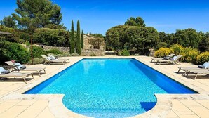 A rectangular swimming pool with a clear blue water surface, surrounded by beige tiles and a stone wall. - Gorgeous in Gordes, Elegantly Furnished with Pool, Tennis and Views  (Gordes)