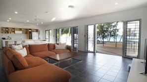 Una sala de estar moderna con un sofá, una mesa de centro y vistas al exterior a través de grandes puertas correderas.
